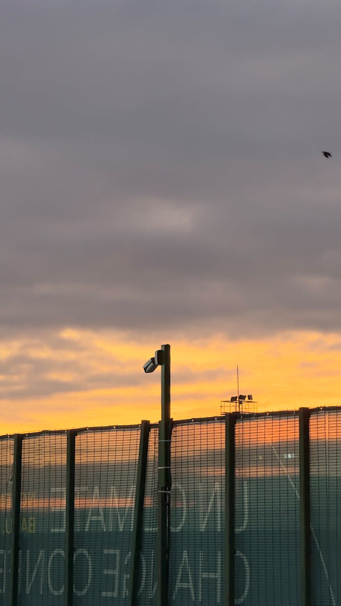Skyline view in Baku with sunset hues and security fence in foreground.